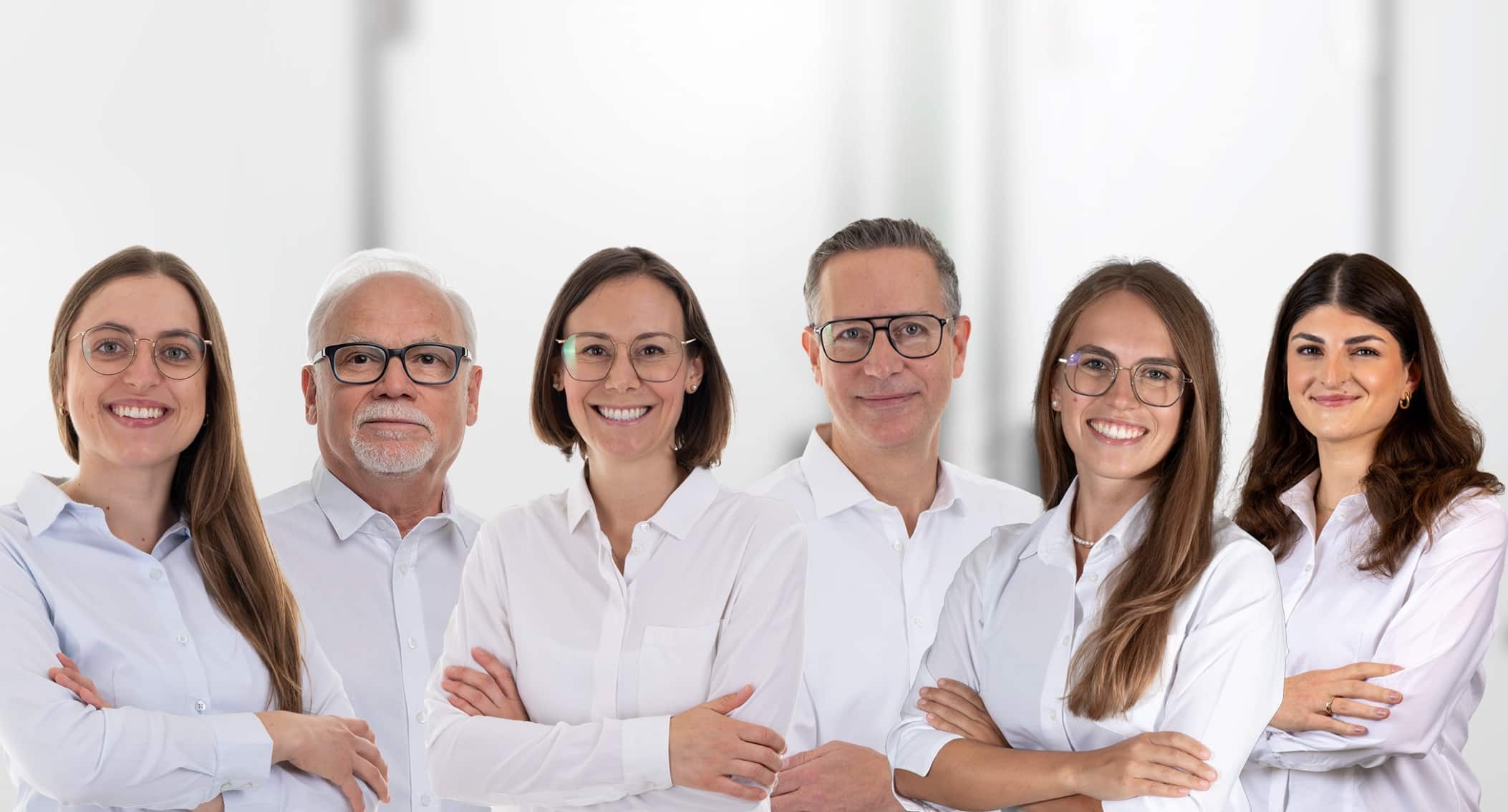 Sechs Zahnärztinnen und Zahnärzte der Praxis Dres. Locher & Partner in weißen Hemden mit verschränkten Armen